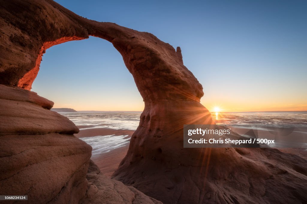 Sun behind rocky arch