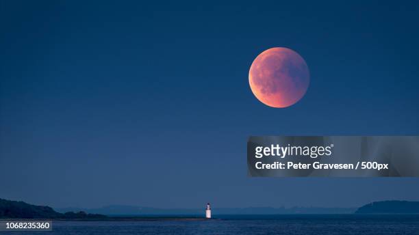 large red moon rising - medias lunas fotografías e imágenes de stock