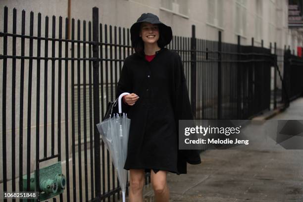 Model Michelle Meinert in a large black rain hat, black one-piece dress, and clear umbrella after the 3.1 Phillip Lim show during New York Fashion...