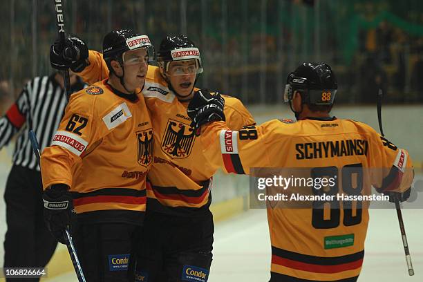Simon Danner of Germany celebrates scoring his first team goal with his team mates Justin Krueger and Martin Schymainski during the German Ice Hockey...