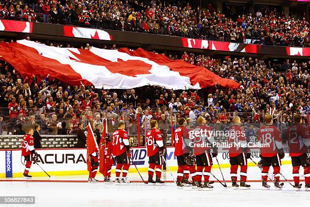 The Ottawa Senators stand at the blue line as the Canadian flag passes through the crowd prior to a game against the Vancouver Canucks on Remembrance...