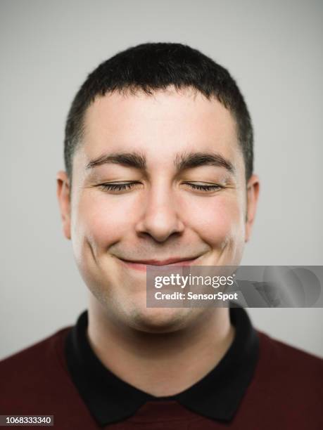 portrait of a young caucassian man closing eyes and smiling - satisfação imagens e fotografias de stock