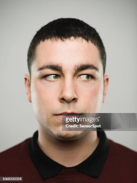 porträt von einem echten junge caucassian mann wegsehen. - annoyed face brunnette stock-fotos und bilder