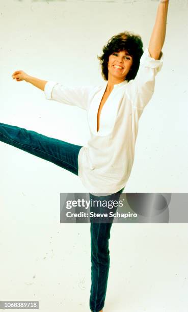 Portrait of American actress Ali MacGraw as she poses, balanced on one leg, in front of a white background, Los Angeles, California, 1982.