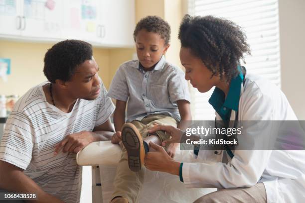 female doctor examining small boy reflexes - reflex hammer stock pictures, royalty-free photos & images