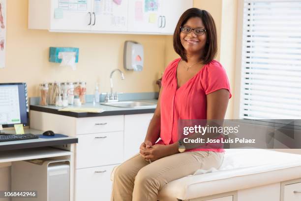 young pregnant woman sitting on examination table - sala de exame médico imagens e fotografias de stock