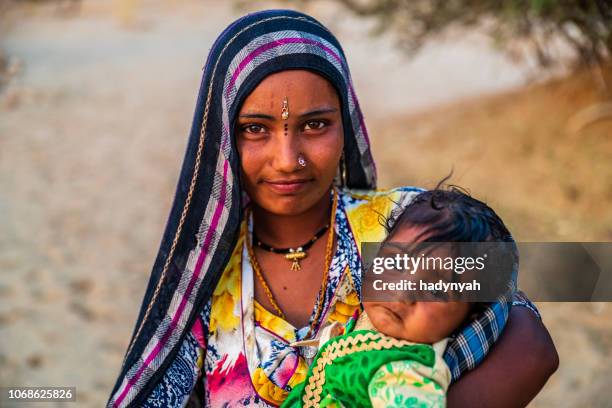 young indian woman holding her baby, desert village, india - rajasthani youth stock pictures, royalty-free photos & images