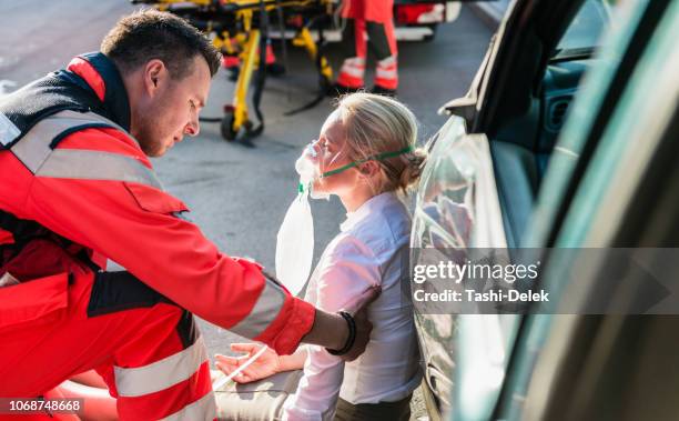 paramédico hombre ayudando a heridos mujer - injured street fotografías e imágenes de stock