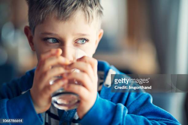 ritratto di un bambino carino che beve un bicchiere d'acqua - acqua potabile foto e immagini stock