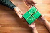 Male gives a gift present to female with wooden copy space background.happiness moment