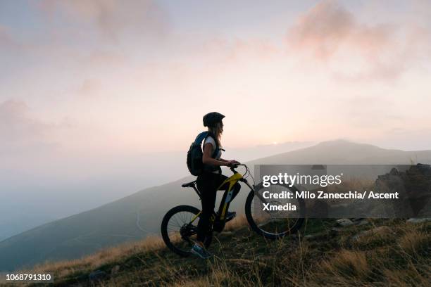 female mountain biker pauses in alpine track, sunrise - bike winning imagens e fotografias de stock