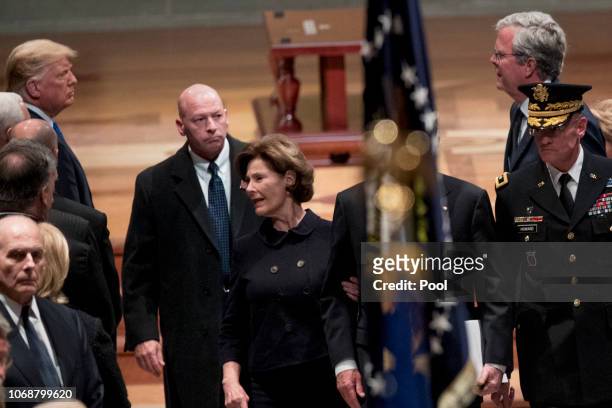 President Donald Trump, left, looks at former Florida Gov. Jeb Bush, right, as Bush family members follow the flag-draped casket of former President...