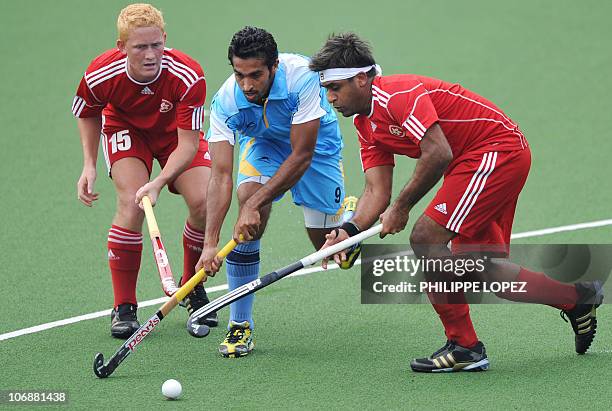 Dharamvir Singh of India tries to dribble two Hong Kong players during a field hockey match of the men's preliminary group A at the 16th Asian Games...