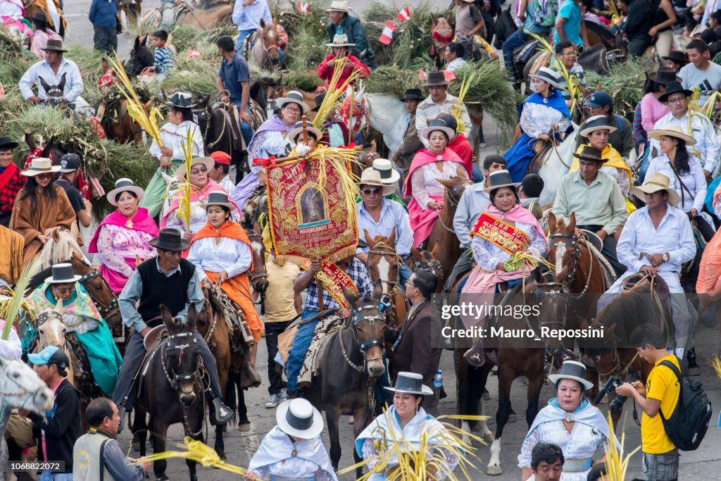 People wearing multicolored dresses and hats riding on horses during the celebration of the Palm Sunday of Easter