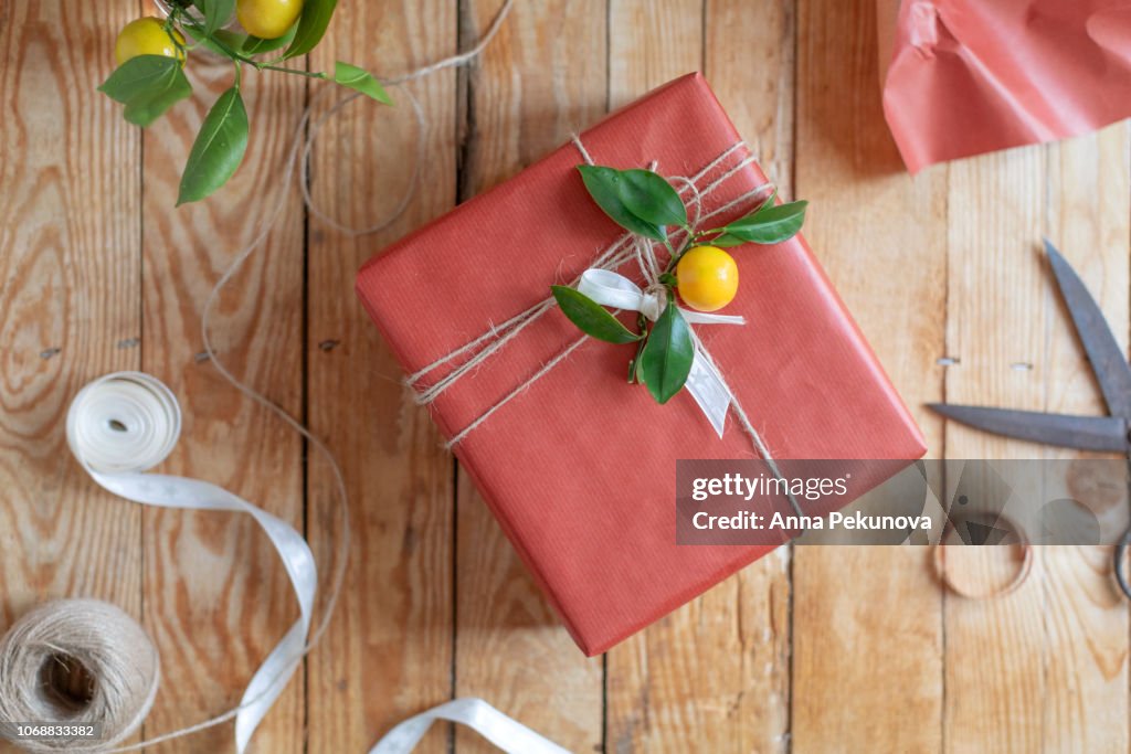 Present wrapped in red paper decorated with branch of mandarine tree