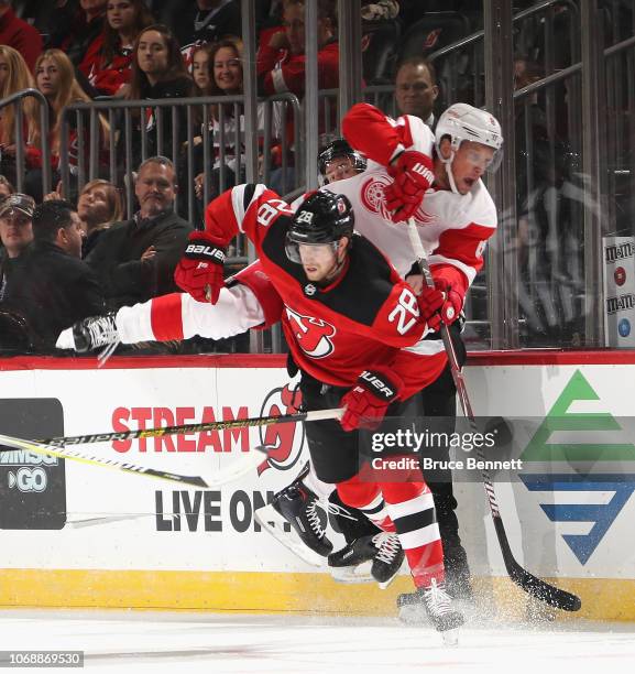 Damon Severson of the New Jersey Devils puts a first period hit on Justin Abdelkader of the Detroit Red Wings at the Prudential Center on November...