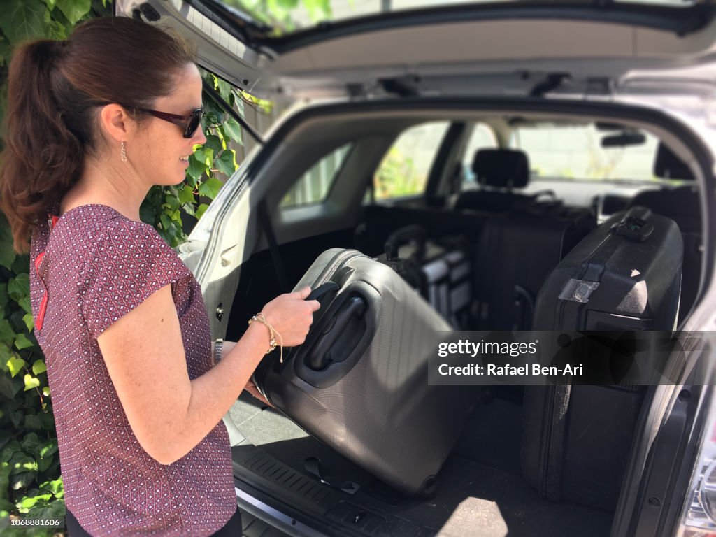 Woman Packing/Unpacking Suitcases from a Car Boot