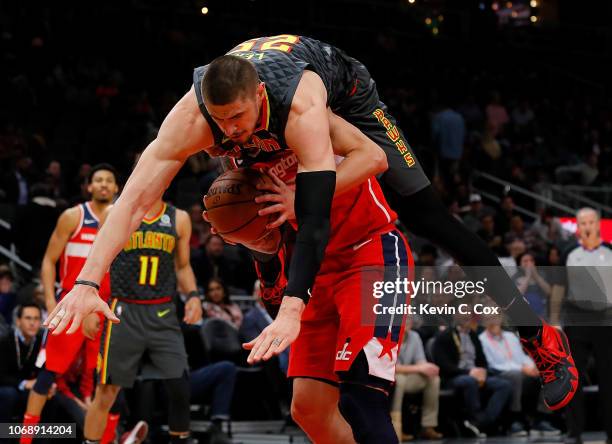 Alex Len of the Atlanta Hawks is charged with a foul as he falls over top of Austin Rivers of the Washington Wizards at State Farm Arena on December...