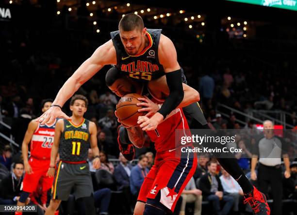 Alex Len of the Atlanta Hawks is charged with a foul as he falls over top of Austin Rivers of the Washington Wizards at State Farm Arena on December...