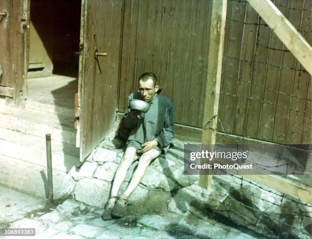 An emaciated former prisoner of the Buchenwald concentration camp drinks from a metal bowl shortly after the camp's liberation, Weimar, Germany, 1945.