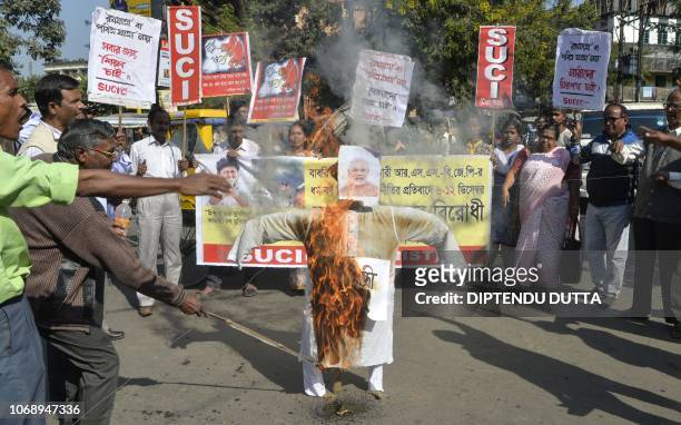 Indian supporters of Socialist Unity Centre of India shout slogans as they burn an effigy of Indian Prime Minister Narendra Modi during a protest to...