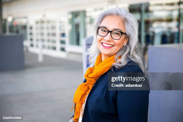 senior mujer hispana fuera del aeropuerto - 55 59 años fotografías e imágenes de stock