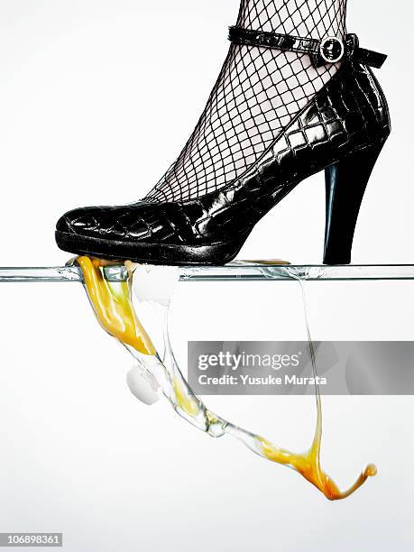 heel stepping on egg  - woman in broken shoe heel stockfoto's en -beelden