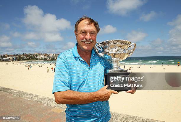 Former tennis player John Newcombe poses with the Norman Brookes Challenge Cup during the Australian Open Trophy Tour at Bondi Beach on November 16,...