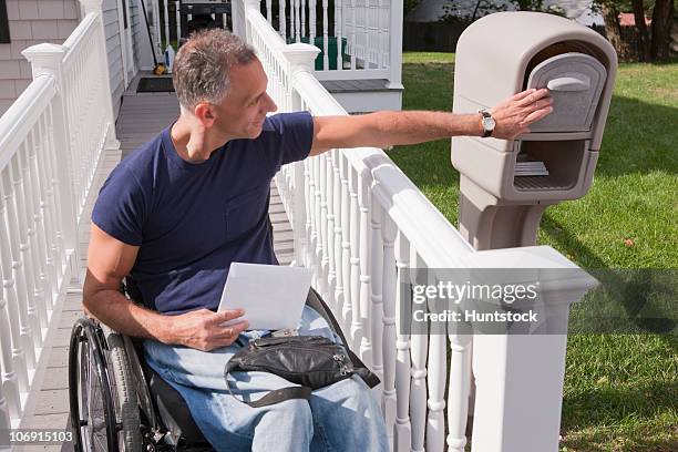 man with spinal cord injury in a wheelchair getting his mail - acceso para sillas de ruedas fotografías e imágenes de stock