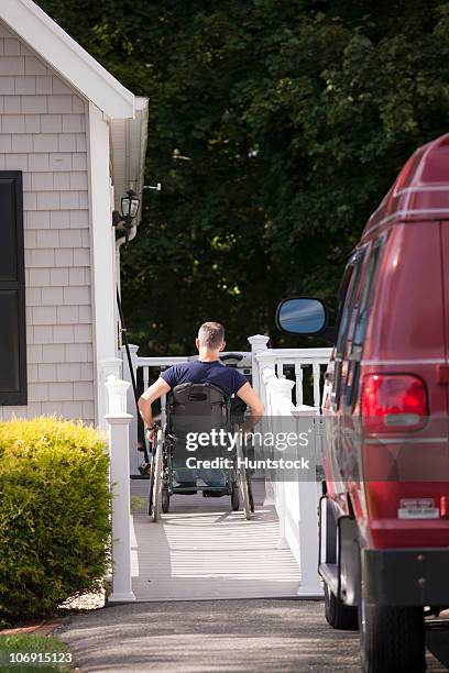 man with spinal cord injury in a wheelchair going up home ramp - wheelchair ramp stock pictures, royalty-free photos & images