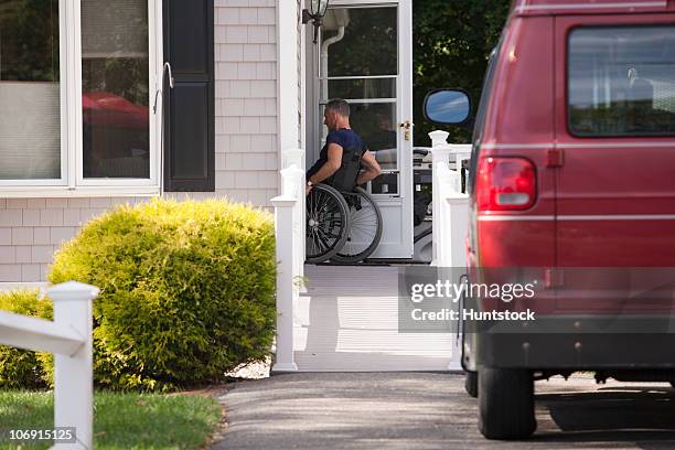 man with spinal cord injury in a wheelchair going up home ramp and in the door - wheelchair ramp stock pictures, royalty-free photos & images