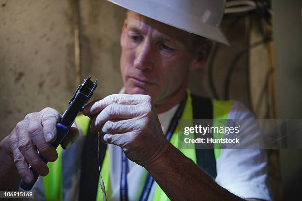 cable installer putting connector on a wire in the cellar of a house - cable installer stockfoto's en -beelden