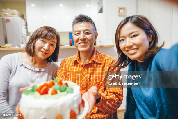 famiglia che festeggia il compleanno a casa - parents children blow candles asians foto e immagini stock