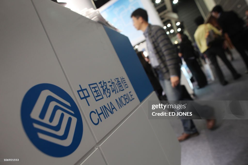 Visitors walk past a stand for China Mob