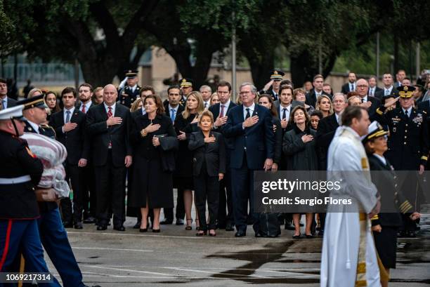 Friends and Bush family members salute and hold their hands over their hearts as they wait for the casket of former President George H.W. Bush on...