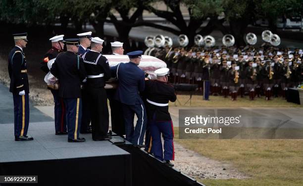 The flag-draped casket of former President George H.W. Bush is carried from the train by a joint services military honor guard on December 6, 2018 in...