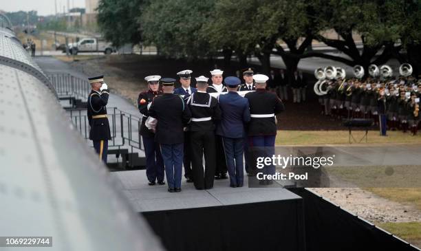 The flag-draped casket of former President George H.W. Bush is carried from the train by a joint services military honor guard on December 6, 2018 in...