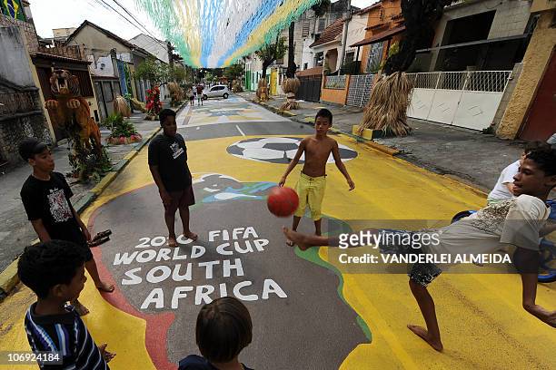 Children play football in a street of Rio de Janeiro decorated with colors of the Brazilian football team and themes from Africa, ahead of the FIFA...