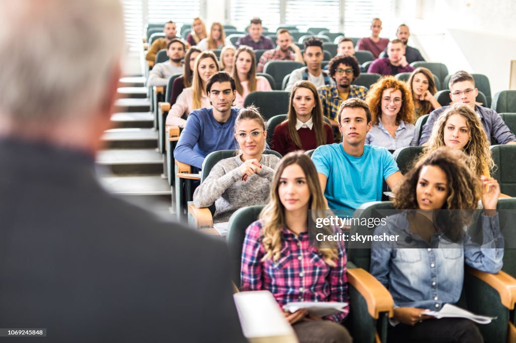 Large group of college students listening to their professor on a class.