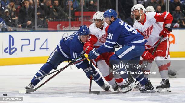 Andreas Athanasiou of the Detroit Red Wings tries to squeeze between Zach Hyman and John Tavares of the Toronto Maple Leafs during an NHL game at...