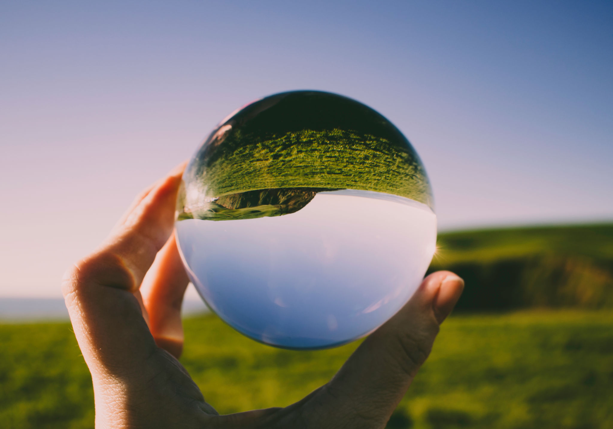 Mão segurando uma esfera com reflxo invertido da imagem de fundo: nova persperctiva, novo olhar Mão segurando uma esfera com reflxo invertido da imagem de fundo: nova persperctiva, novo olhar