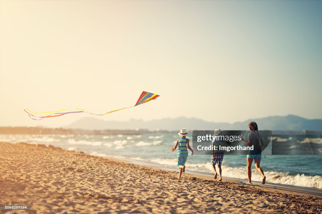 Kinder laufen mit Kite am Strand