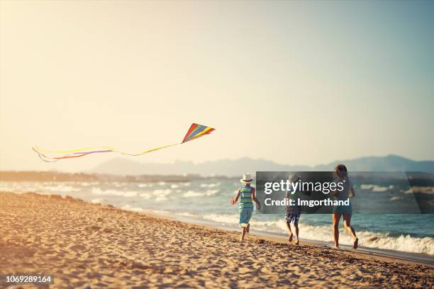 kinderen lopen met kite op een strand - people flying kites stockfoto's en -beelden