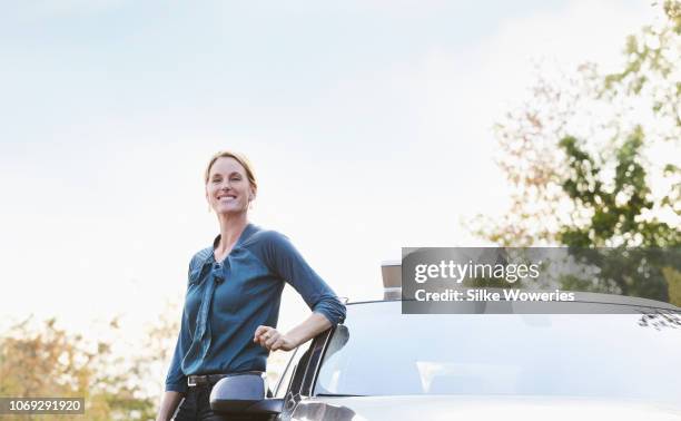 portrait of a mid adult businesswoman standing beside her car - driver portrait fotografías e imágenes de stock