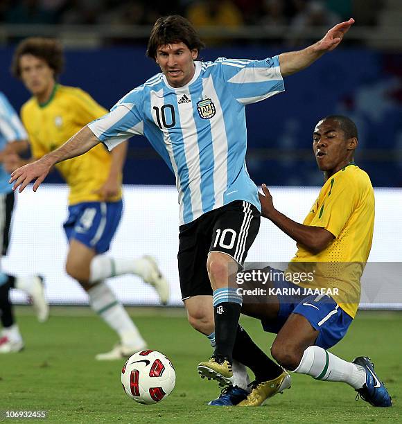Argentina's striker Lionel Messi is challenged by Brazil's midfielder Ramires during their friendly football match at Khalifa Stadium in the Qatari...