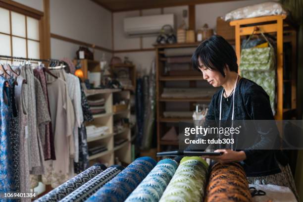 Mature woman inspecting the finished textile fabric she designed after manufacturing