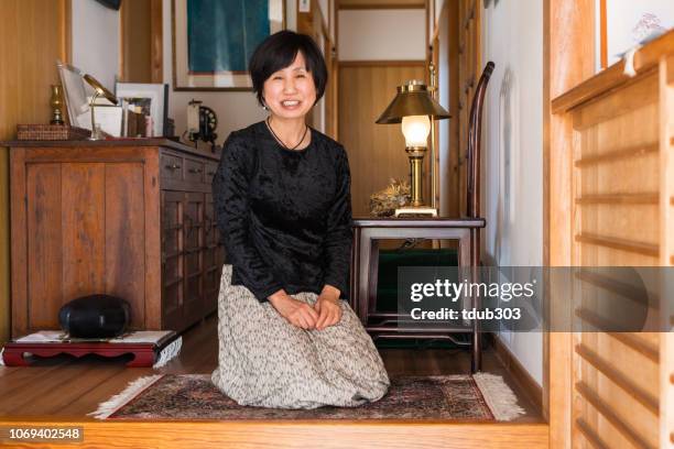 mature woman sitting in the entrance way of her home in japan - one woman only kneeling stock pictures, royalty-free photos & images