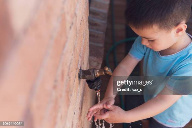 kleiner junge seinem händewaschen an einer outdoor-armatur - neuseeländische kultur stock-fotos und bilder