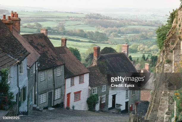 View of thatched cottages and the cobbles of Gold Hill in Shaftesbury which runs steeply down rural Blackmoor Vale, Dorset, May 1984. Many of the...