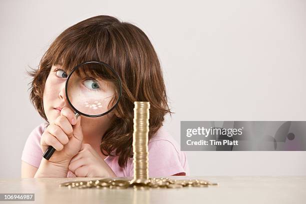 young girl with magnifying glass and pile of coins - kids money fotografías e imágenes de stock
